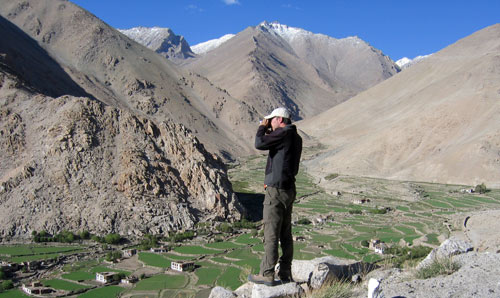 Photograph of a hiker looking down from a hillside on a village