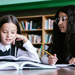 Two young girls studying a book in a library