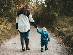 Mother and child walking down a path in a forest