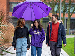 3 students under a purple umbrella