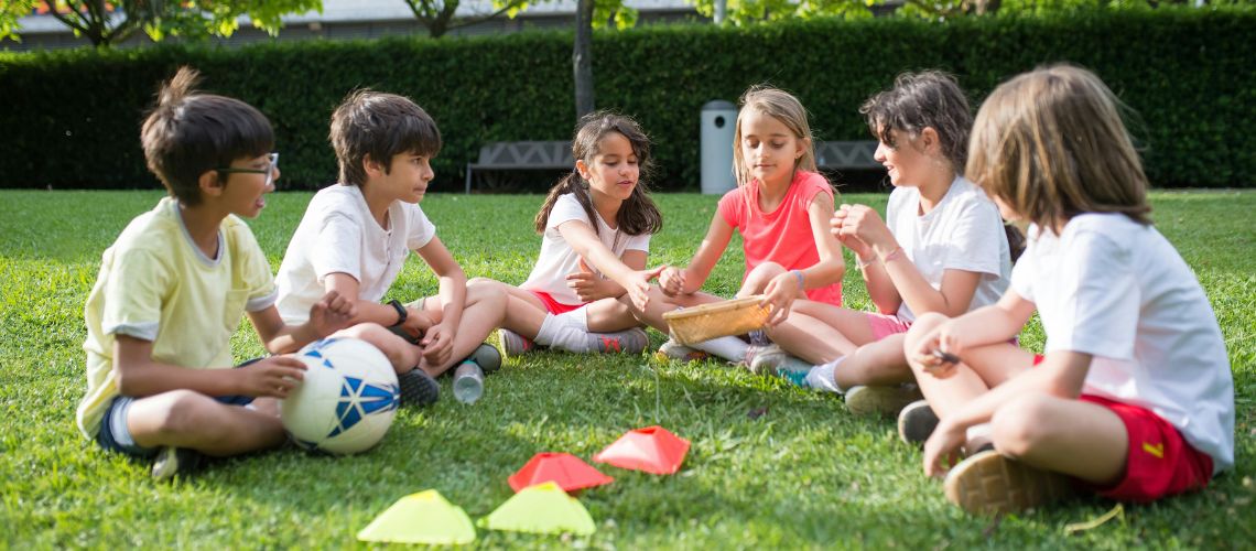 Children sat in a semi-circle on grass
