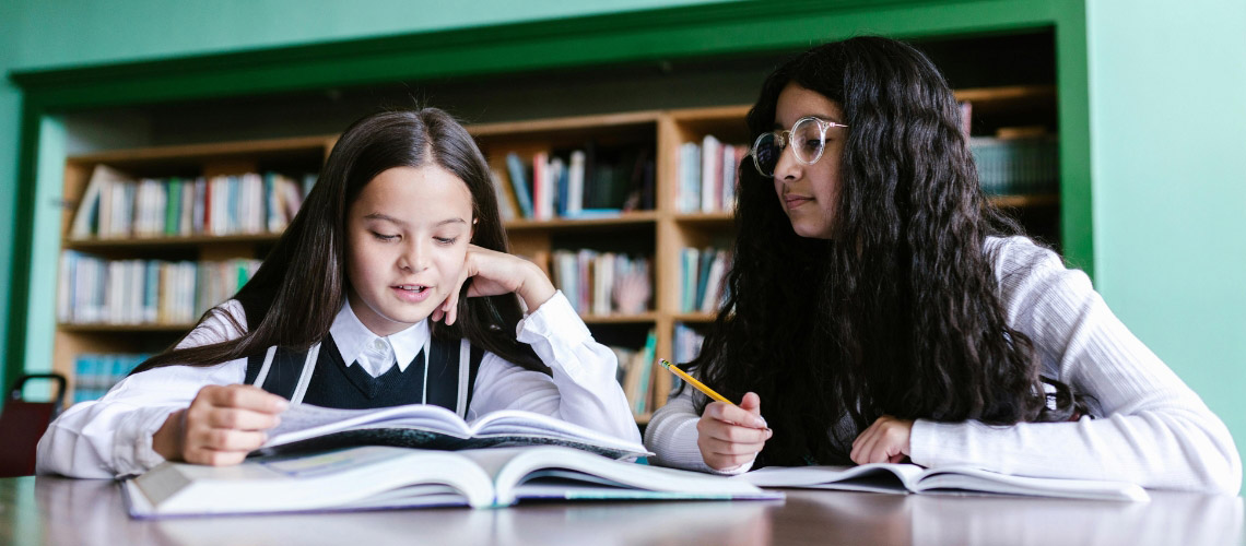 Two children reading a book together in a library
