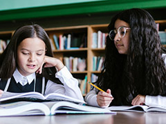 Two girls reading a book together in a library