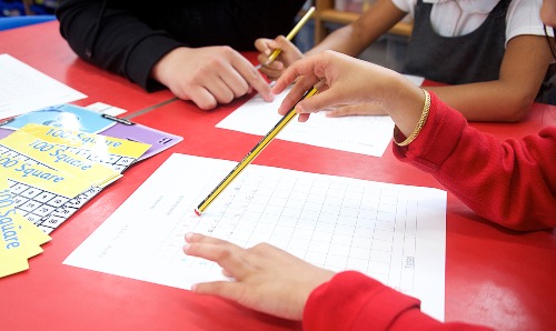 Primary teacher sat with pupil.