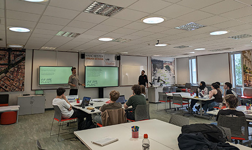 Students watch a We Are Planit presentation in the Manchester Urban Design Lab studio classroom.