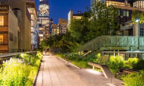 Panoramic view of the High Line promenade (Chelsea, Manhattan, New York City) at twilight with city lights and illuminated skyscrapers.