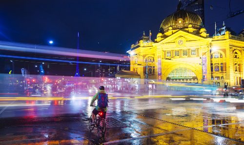 View of a crossroad outside Flinders Street Railway Station in downtown Melbourne, Australia, at night.