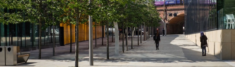 People walking down pedestrianized area of Manchester.