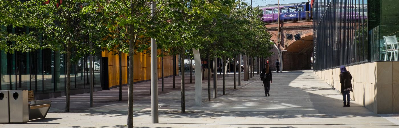 People walking down pedestrianized area of Manchester.